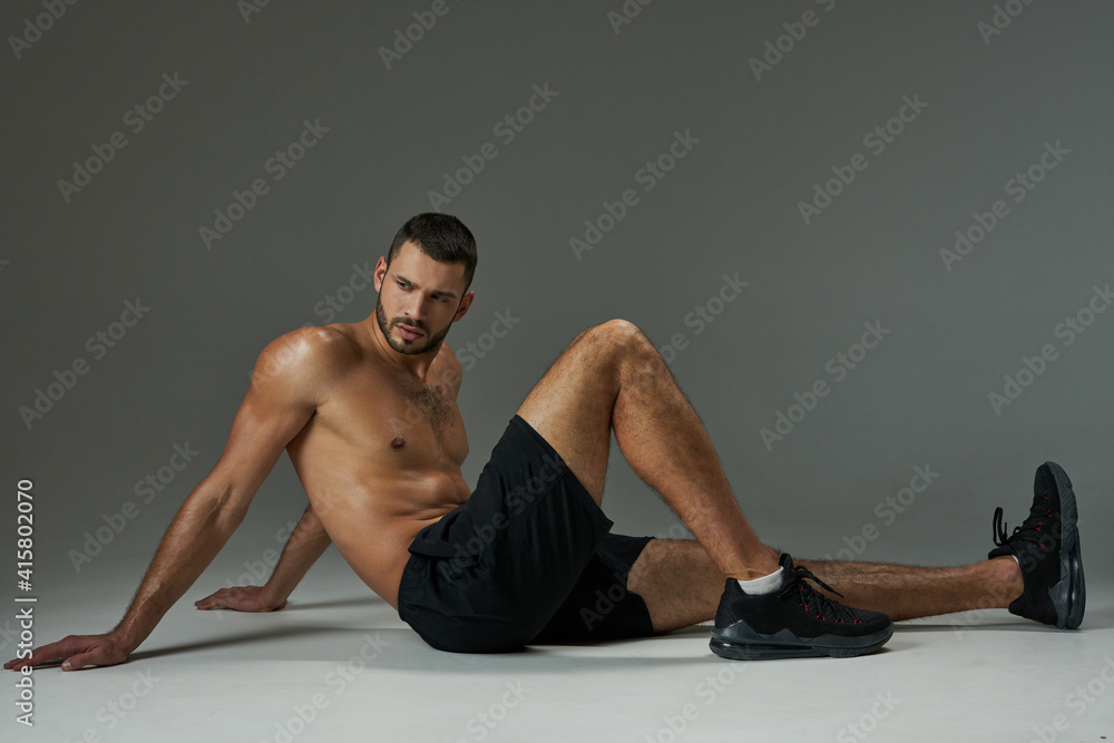 Obraz premium Handsome adult Caucasian sportsman in sportswear relaxing after training isolated on grey background
