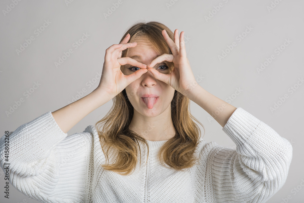 Portrait of a stylish and cheerful girl on a white background in the studio who shows funny grimaces Portrait of a stylish and cheerful girl on a white background in the studio who shows funny grimaces