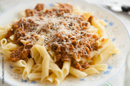 Close up home made pasta dish with bolognese meat sauce and grated parmesano cheese on top. 