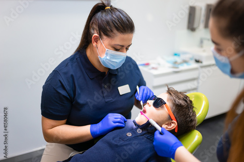Photos Dentist and assistant make preventive dental plaque cleaning for teenager