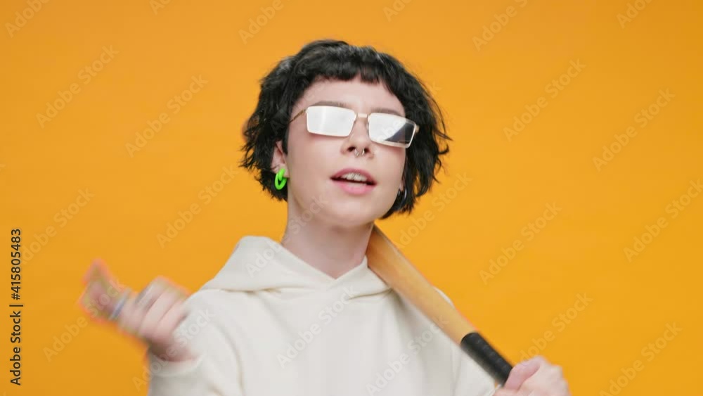 Protest Teenage Girl Dancing and Singing on Yellow Background with Baseball Bat in her Hands, with Piercings, Sunglasses Smiling, Rhythmically Moving Hands in front of Camera Funny dance. Freedom Protest Teenage Girl Dancing and Singing on Yellow Background with Baseball Bat in her Hands, with Piercings, Sunglasses Smiling, Rhythmically Moving Hands in front of Camera Funny dance. Freedom