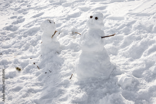 Two happy snowman on a snowy field.