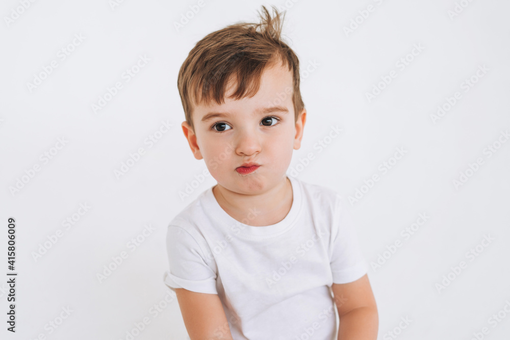 Funny cute thoughtful toddler boy in white t-shirt on the white background Funny cute thoughtful toddler boy in white t-shirt on the white background