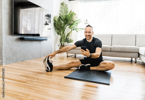 Man on a mat doing some exercise at home using cellphone to help training