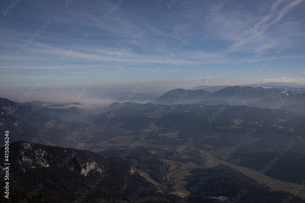 Scenic view from Rax, Austria, over the valley with mountain ranges disappearing in the distance in the go and the clouds.