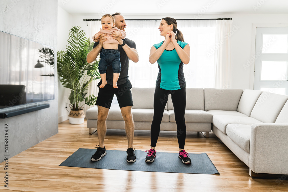 Fototapeta premium Happy couple training with his baby the baby looks at someone.