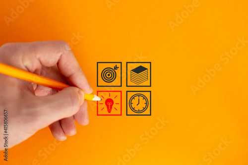 Close up of businessman hand drawing business strategy sketches. Time, idea, books, target. Yellow background.
