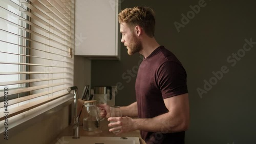 Wallpaper Mural A pleased man is drinking fresh water while standing in the kitchen at home in the morning Torontodigital.ca