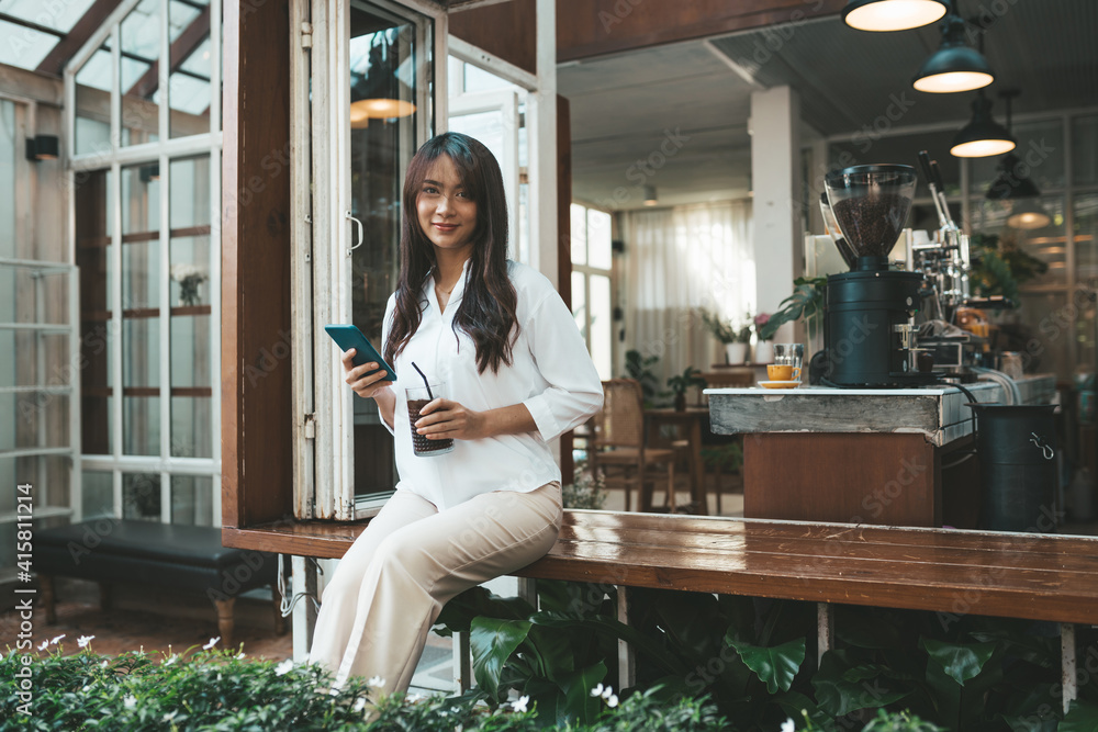 Cute asian young woman sitting in cafe with coffee and phone Cute asian young woman sitting in cafe with coffee and phone