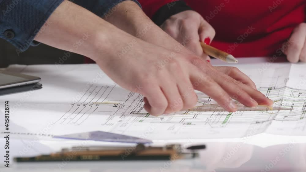 Close-up of people working on architecture plans in office Close-up of people working on architecture plans in office