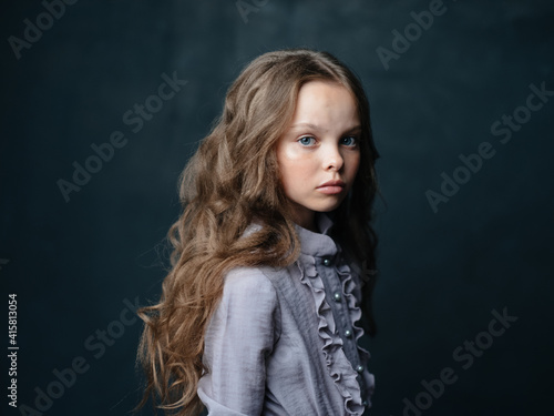 Portrait of a beautiful girl in a gray sundress on a dark background and a curly long hair model