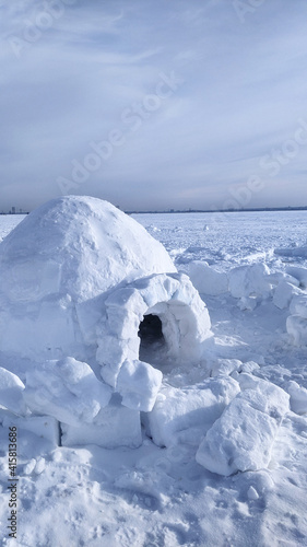 igloo and snow shelter in high snowdrift with mountains peaks on background © Albina