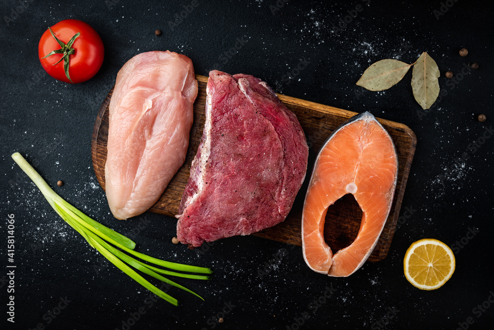Fresh raw meat, salmon and chicken fillet on black background with spices. Natural food high in protein. Top view. Fresh raw meat, salmon and chicken fillet on black background with spices. Natural food high in protein. Top view.