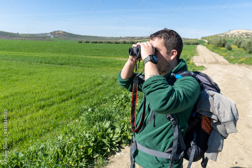 Active man in the countryside looking the landscape using binoculars.