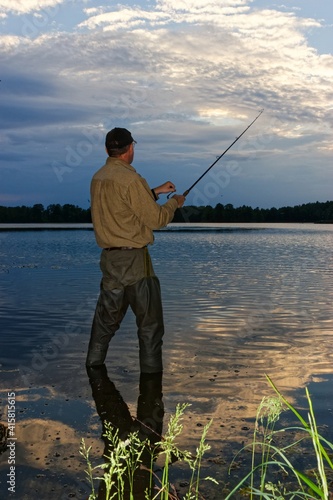 angler catching fish in lake during cloudy day