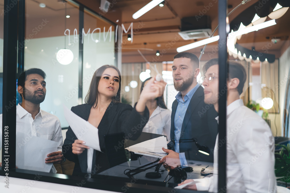 Multiethnic coworkers writing business ideas on glass Multiethnic coworkers writing business ideas on glass
