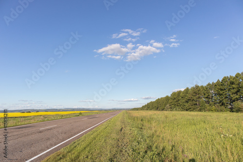 Empty asphalt road and yellow flowers field with the blue sky