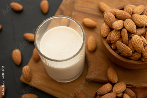 Almond milk with almond in a wooden spoon and bowl on a wooden (selective focus; close-up shot)