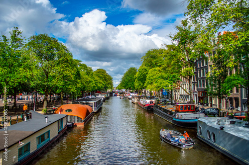 Amsterdam, Netherlands - July 7, 2019: Traditional Dutch houseboats in the canals of Amsterdam in the Netherlands on a sunny summer day