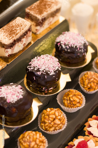 Single serving desserts on a modern stand of a buffet table, wedding candy bar