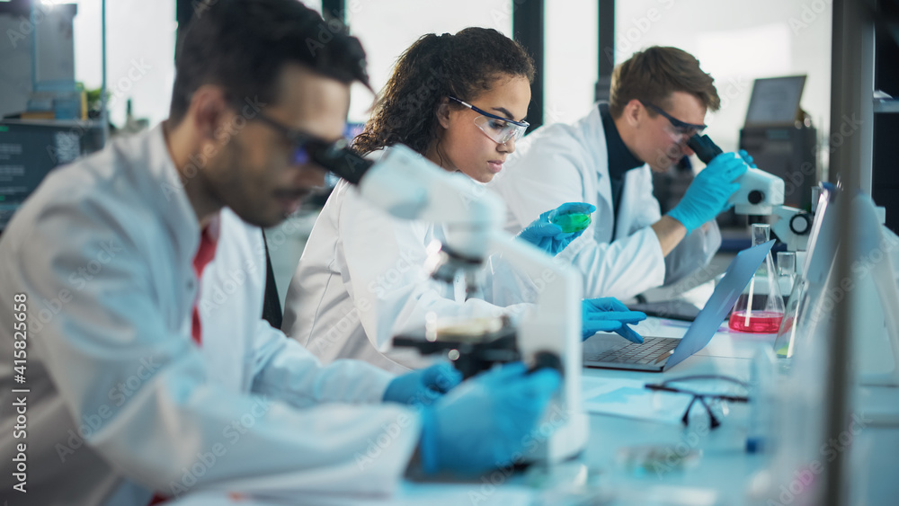 Medical Science Laboratory: Row of Diverse Team of Multi-Ethnic Young Scientists Looking Under Microscope, Analyze Chemicals, Talk, Solving Problems. Biotechnology Specialists working in Advanced Lab Medical Science Laboratory: Row of Diverse Team of Multi-Ethnic Young Scientists Looking Under Microscope, Analyze Chemicals, Talk, Solving Problems. Biotechnology Specialists working in Advanced Lab