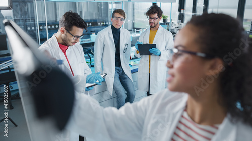 Medical Science Laboratory: Beautiful Black Female Scientist Writes Detailed Project Data Analysis on the Board, Her Diverse Team of Colleague Listens. Young Scientists Solving Problems.