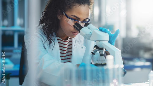 Foto Medical Science Laboratory: Portrait of Beautiful Black Scientist Looking Under Microscope Does Analysis of Test Sample