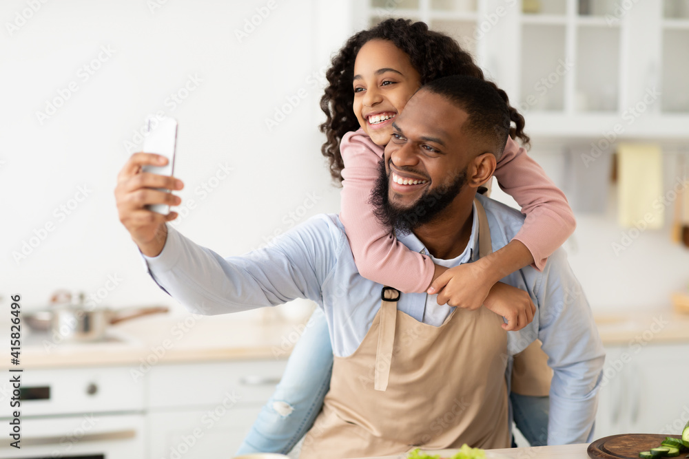 Cheerful african father taking selfie with cute daughter Cheerful african father taking selfie with cute daughter