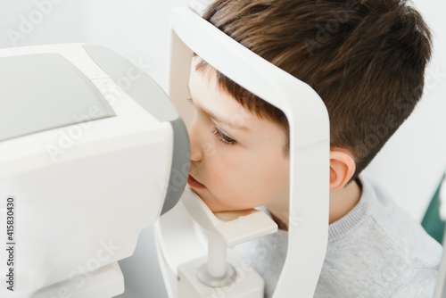 Optometry concept. Female optometrist optician doctor examines eyesight of child boy in eye ophthalmological clinic photo