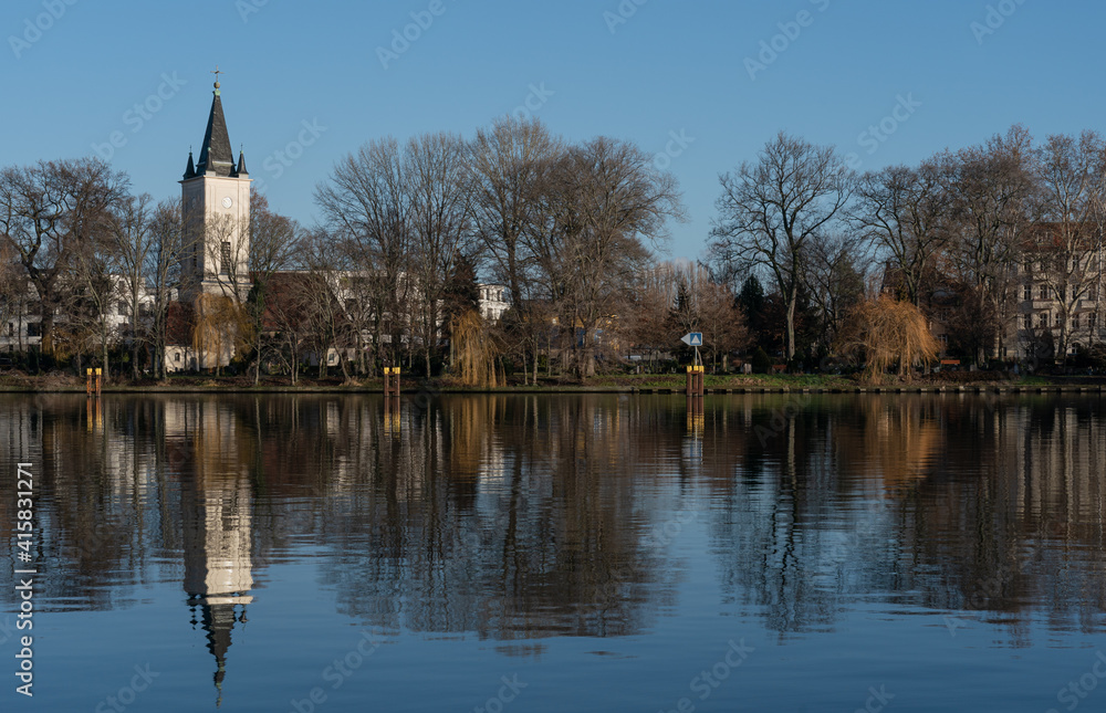 Dorfkirche Stralau in Berlin an einem sonnigen Wintertag mit Spiegelung in der Spree