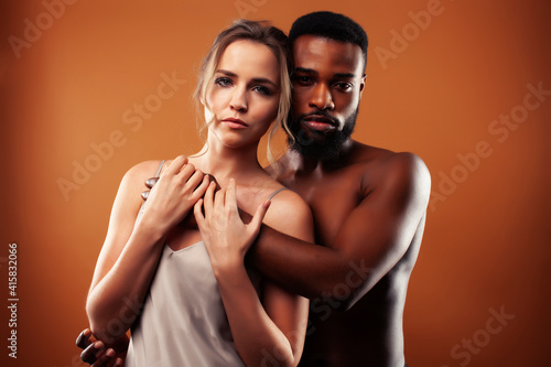 Young pretty couple diverse races together posing sensitive on brown background, lifestyle people concept © iordani