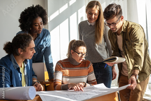 Design students in the classroom.They examining blueprint.	
