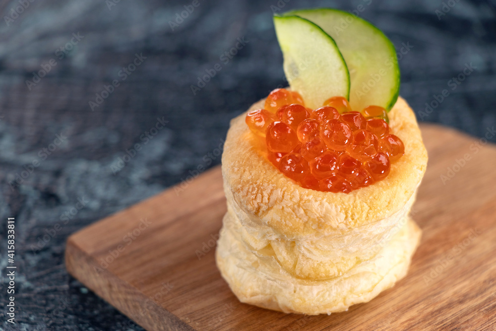Tartlets, red caviar, cucumber on a black table. Appetizer with red caviar. Delicious and healthy snack. Tartlets, red caviar, cucumber on a black table. Appetizer with red caviar. Delicious and healthy snack.