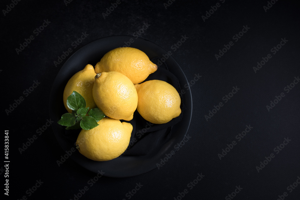 Limones en un plato negro sobre fondo negro. Vista superior