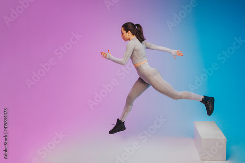 Fashion portrait of young fit and sportive caucasian woman on gradient background. Fit sportswoman posing, looks confident. Perfect body ready for summertime. Beauty, resort, sport concept. Flyer