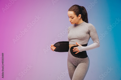 Valokuva Young sportive woman training fitness waist trainer belt back isolated on gradient studio background in neon light