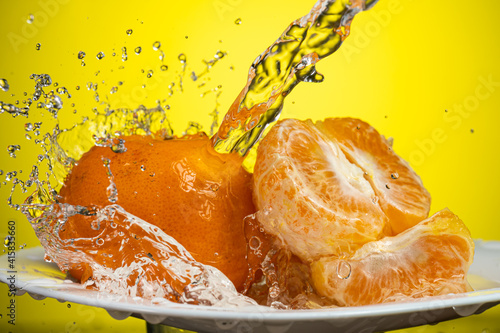 Fototapeta Naklejka Na Ścianę i Meble -  tangerines with splash and flow of water on white or yellow background