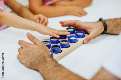 Kid s and man s hands touching wooden toy on white desk. Focus is at the toy.