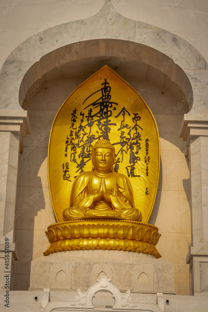 Fototapeta premium Budhha praying golden statue isolated in details from unique perspective