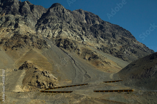 Traveling along the arid cordillera in summer. View of the asphalt highway with tunnels, across the Andes mountain range. 