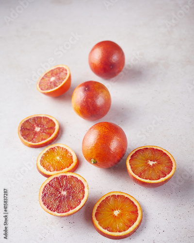 composition of whole and sliced blood oranges on a stone surface