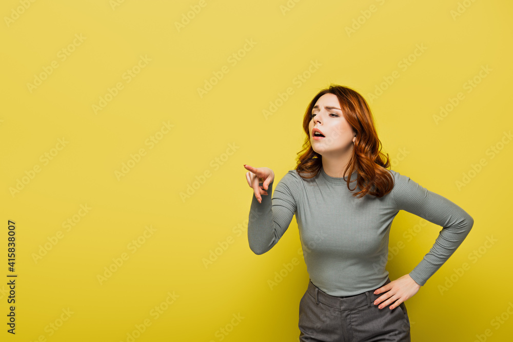 woman with curly hair standing with hand on hip while pointing with finger on yellow woman with curly hair standing with hand on hip while pointing with finger on yellow