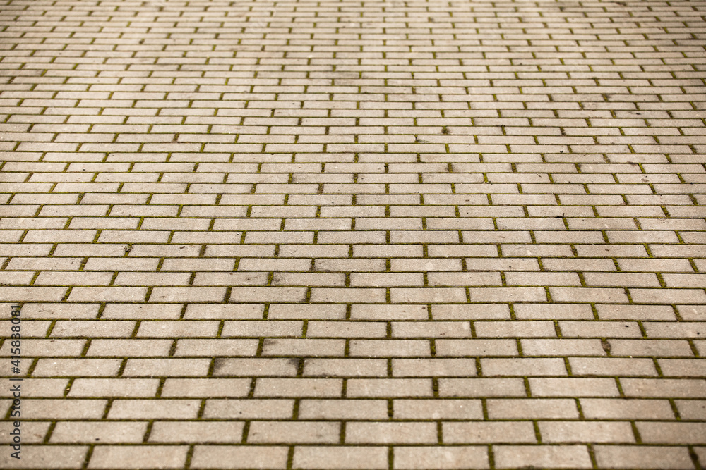 Image of a cobbled road in an urban environment. Paving stones on a footpath or car park in the city. Paving stone pattern in perspective. Natural daylight, cloudy weather.