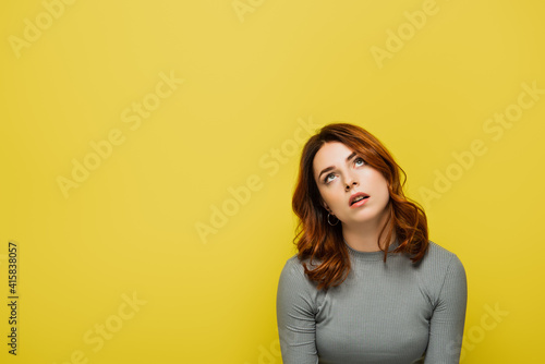 bored woman with curly hair rolling eyes isolated on yellow