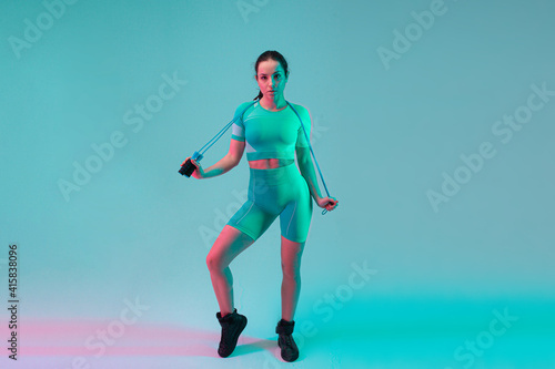 Young fit and sportive woman with rope on gradient background. Fit sportswoman posing  looks confident. Perfect body ready for summertime. Beauty  resort  sport concept