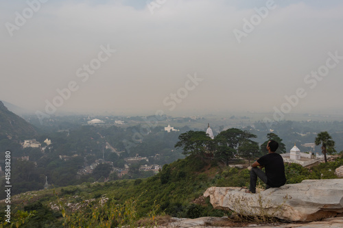 man sitting isolated at rock and watching amazing landscape