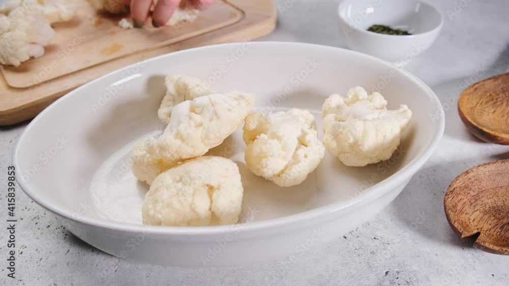 Cooking raw cauliflower with spices and oil on the table. Cooking vegan food concept. Cooking raw cauliflower with spices and oil on the table. Cooking vegan food concept.