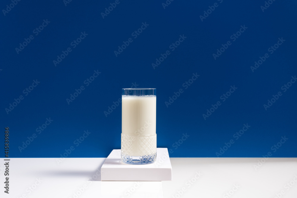 Vaso de leche fresca en mesa blanca sobre fondo azul Vaso de leche fresca en mesa blanca sobre fondo azul