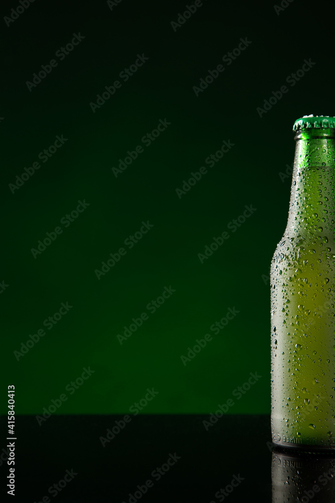 Bottle of cold beer  on dark green background with copyspace. Vertical format.