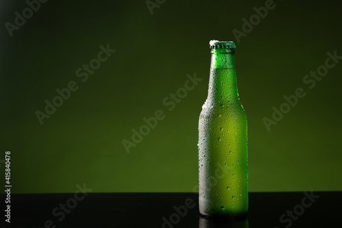 Bottle of cold beer on green background with copyspace.